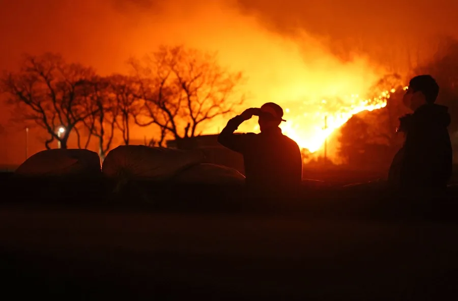 Ciudadanos observan el incendio forestal que se extiende por una ladera cercana en Andong, a unos 190 kilómetros al sureste de Seúl, Corea del Sur.