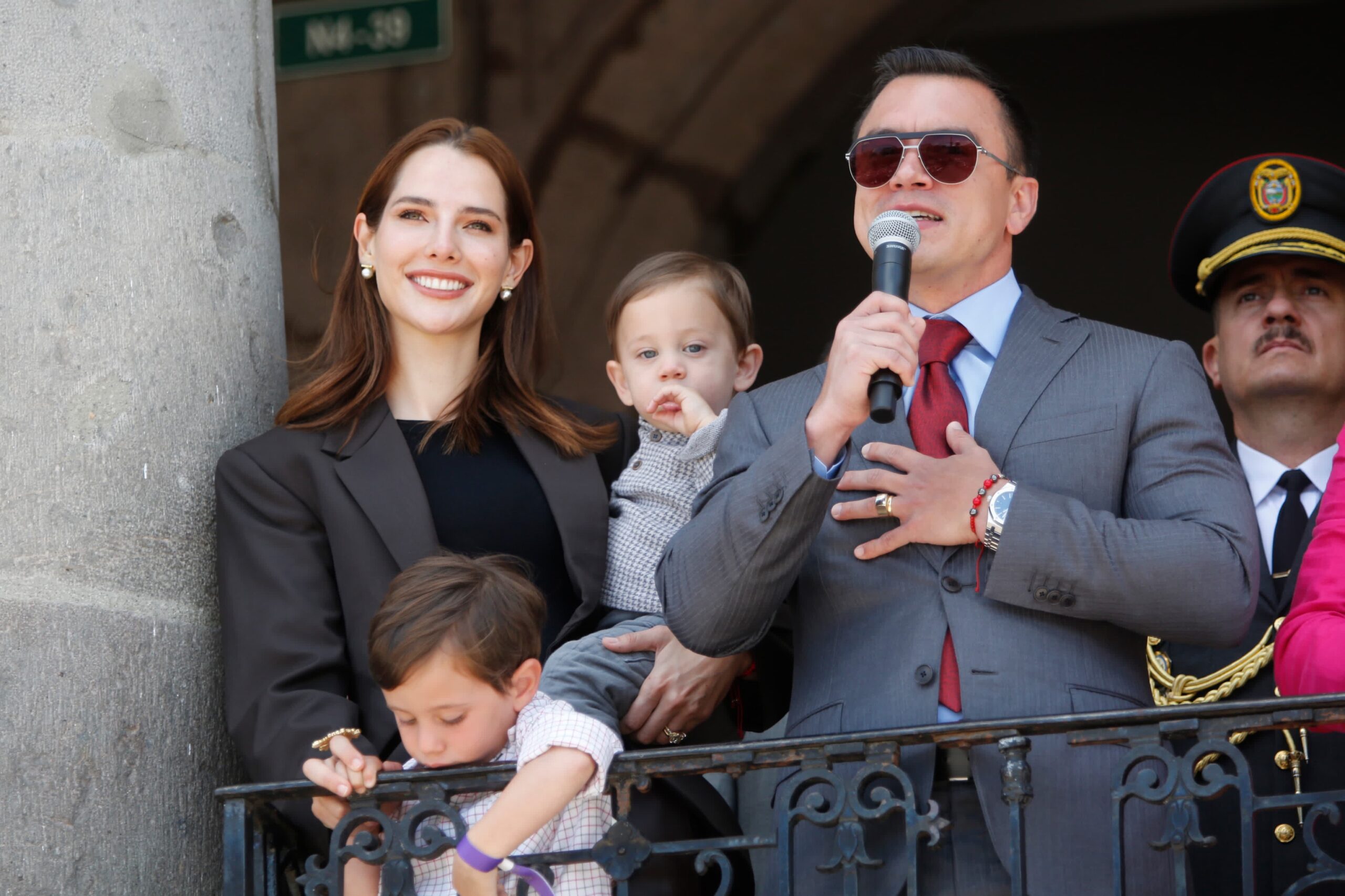 Presidente del Ecuador junto a su familia y un guardia presidencial en un balcón del palacio presidencial.