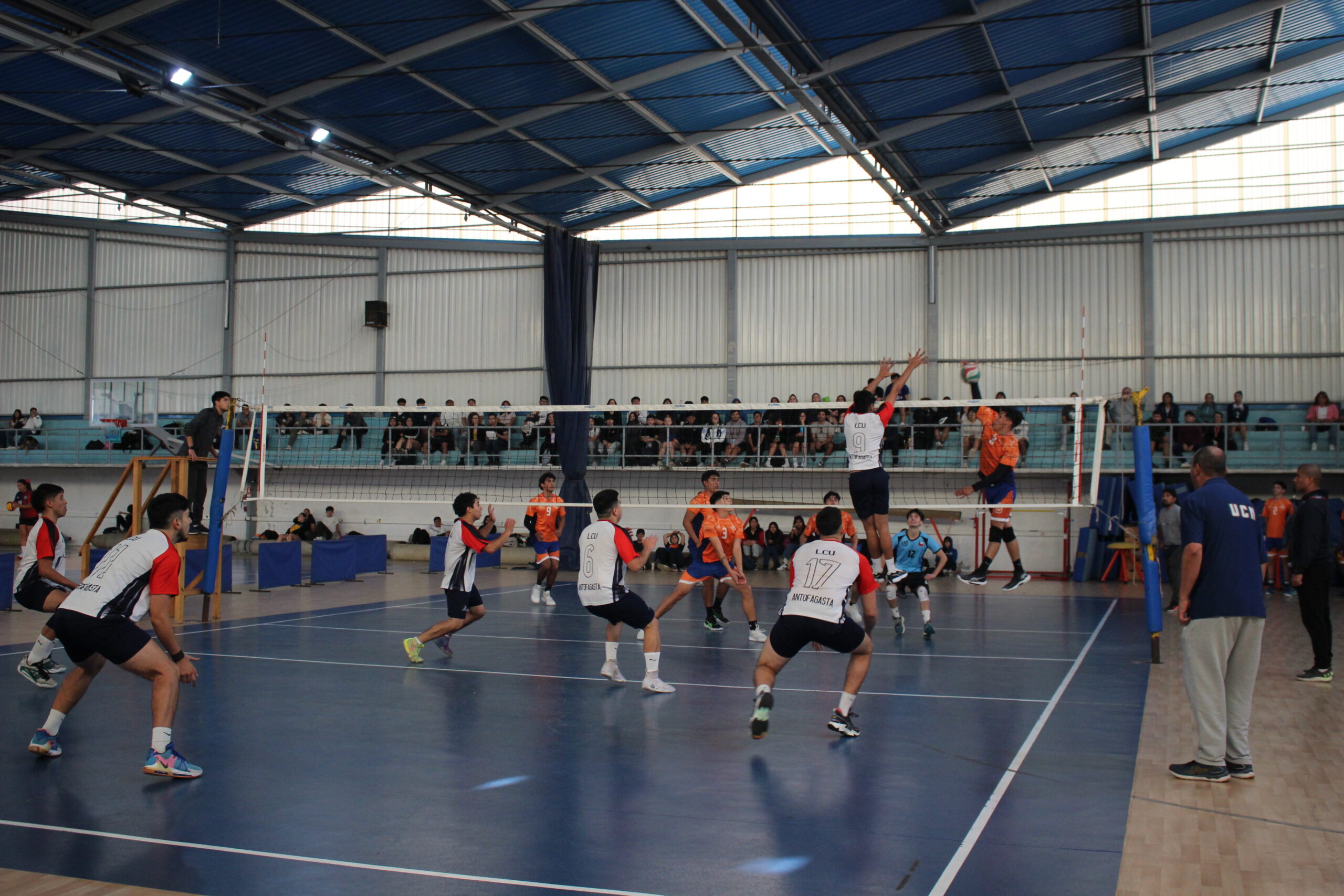 Jugador de la UCN realizando un saque en un partido de voleibol.